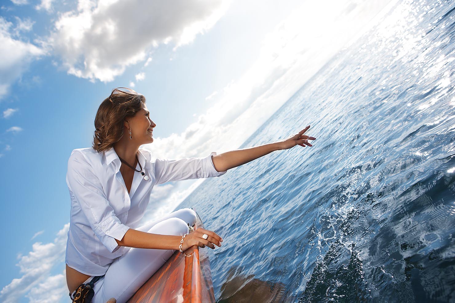 Weibliches Model auf einem Segelboot spritzt mit der Hand im Wasser