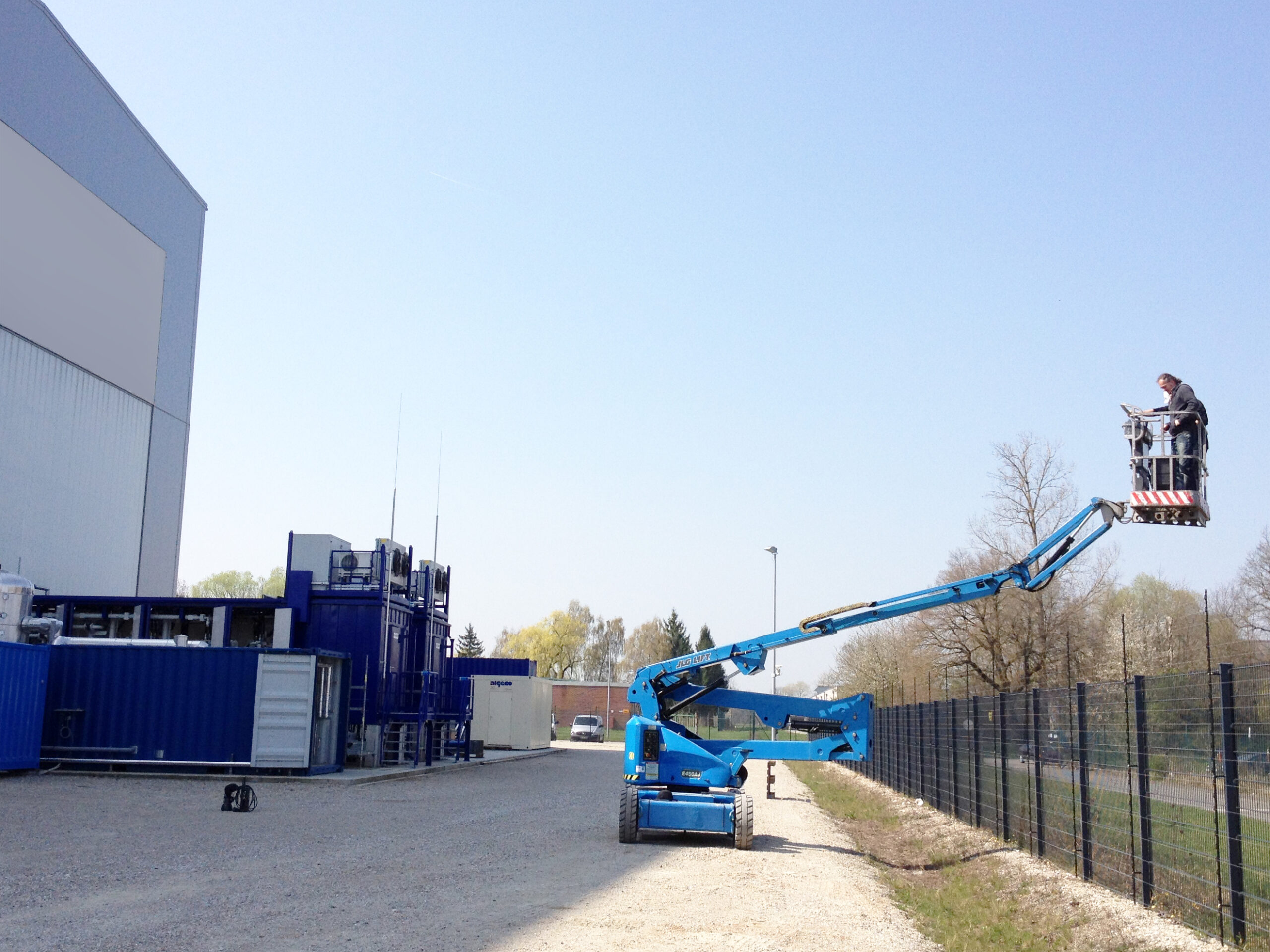 Industriefotograf Kai Arndt steht auf einer Hebebühne und fotografiert eine Industrieanlage